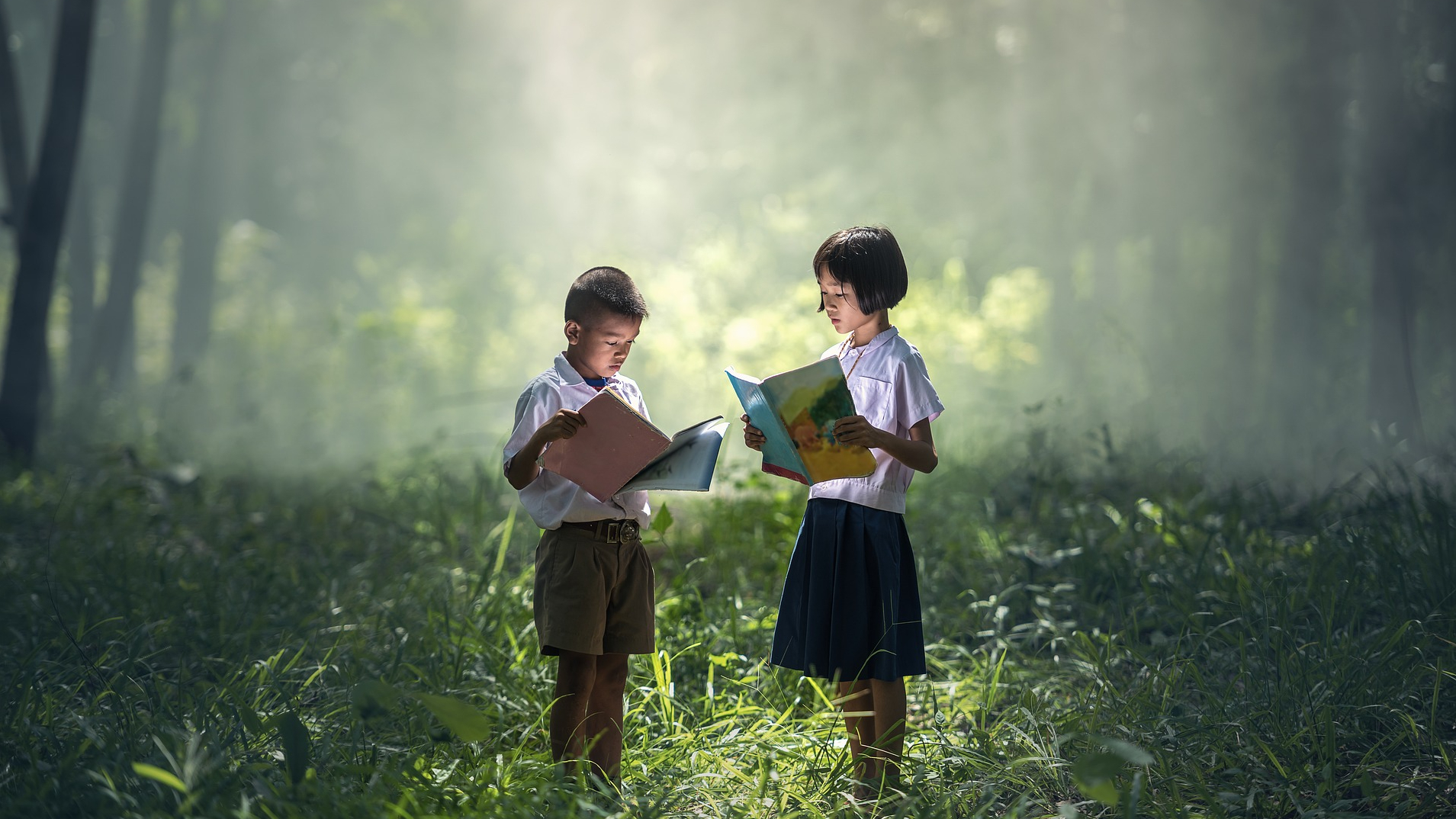 two children reading books in a pretty forest